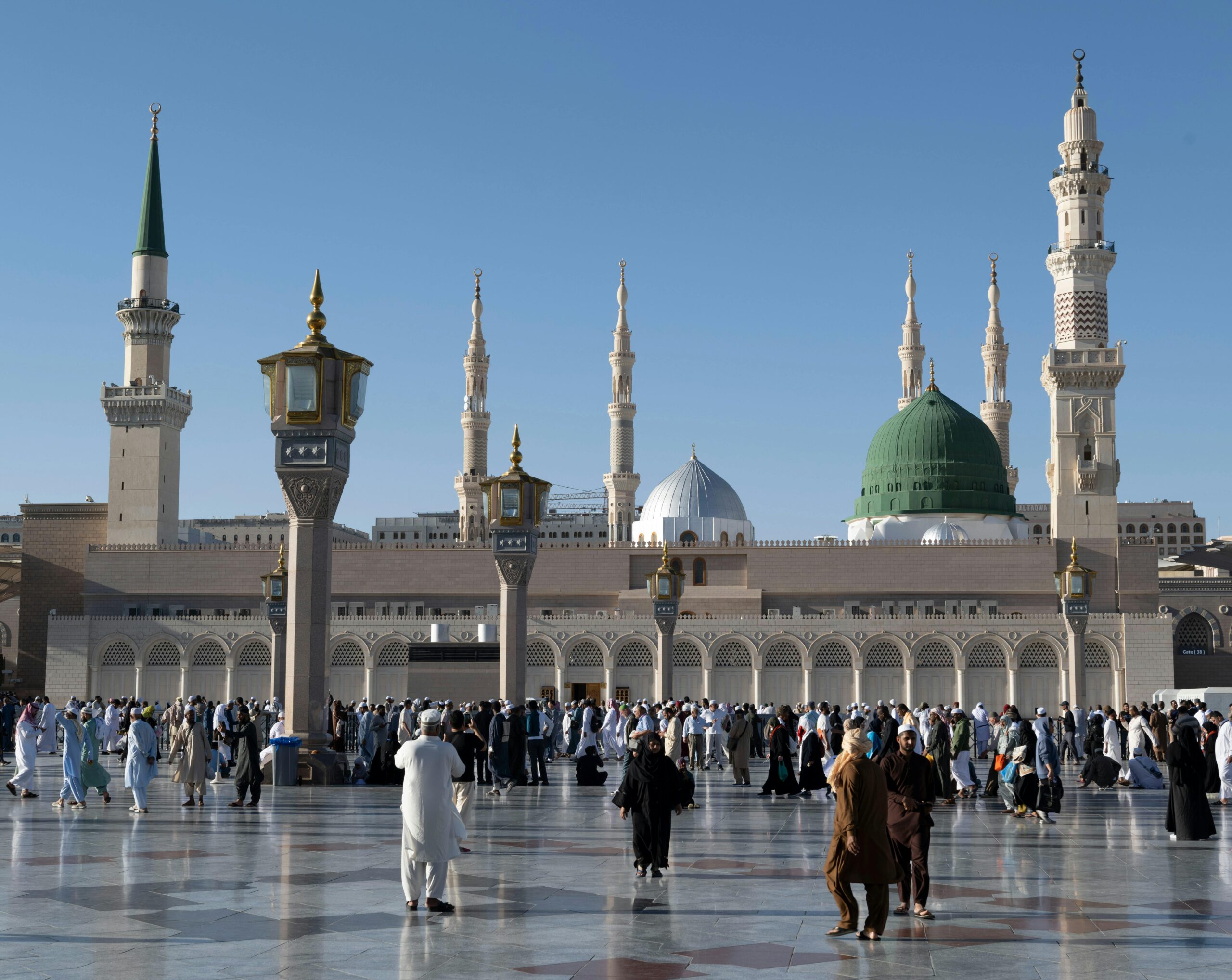 Pilgrims gather at the courtyard of Al-Masjid an-Nabawi, showcasing Islamic architecture in Medina, Saudi Arabia.